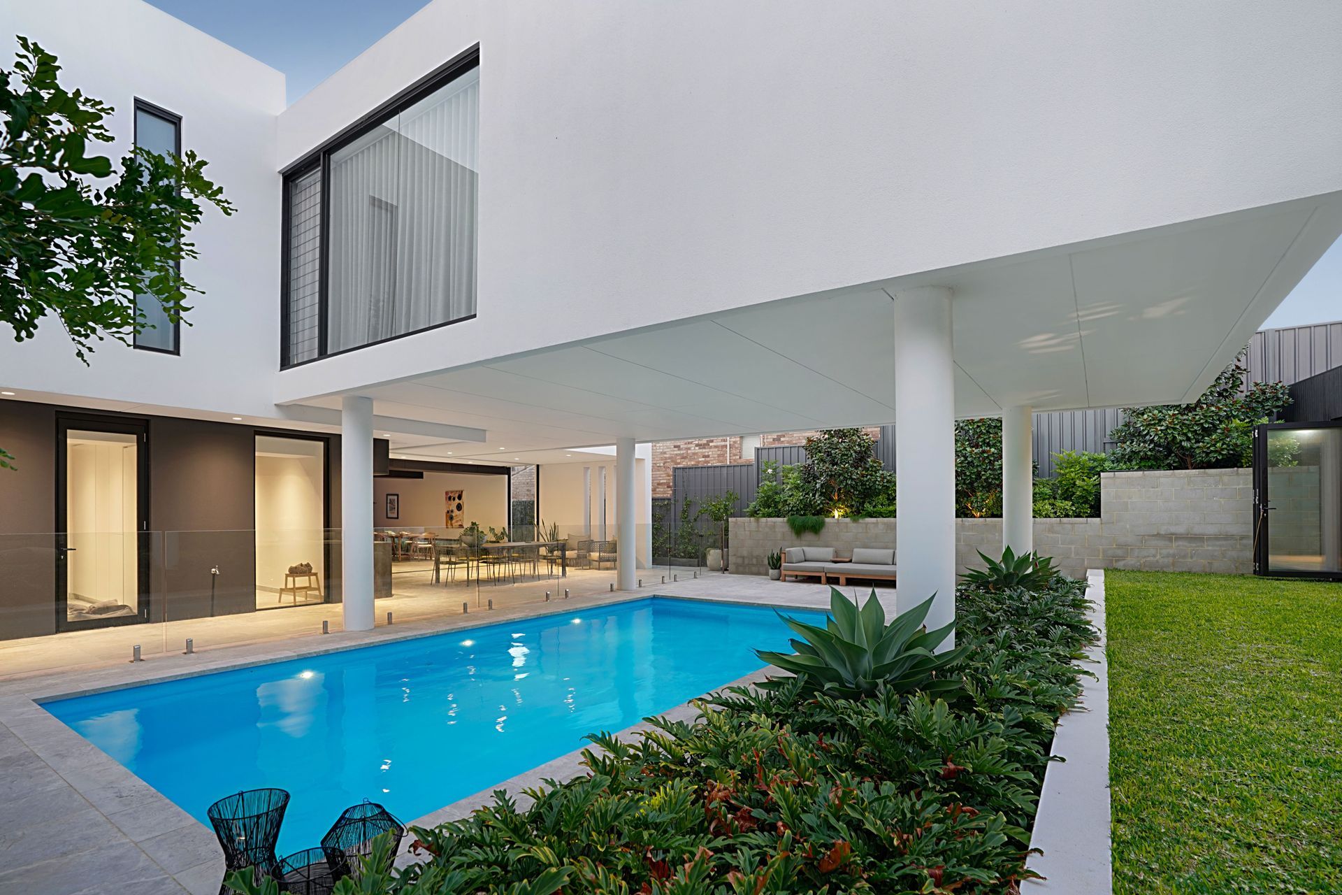 A Large Swimming Pool is Lit Up at Night — Pools By Design in Warana, QLD