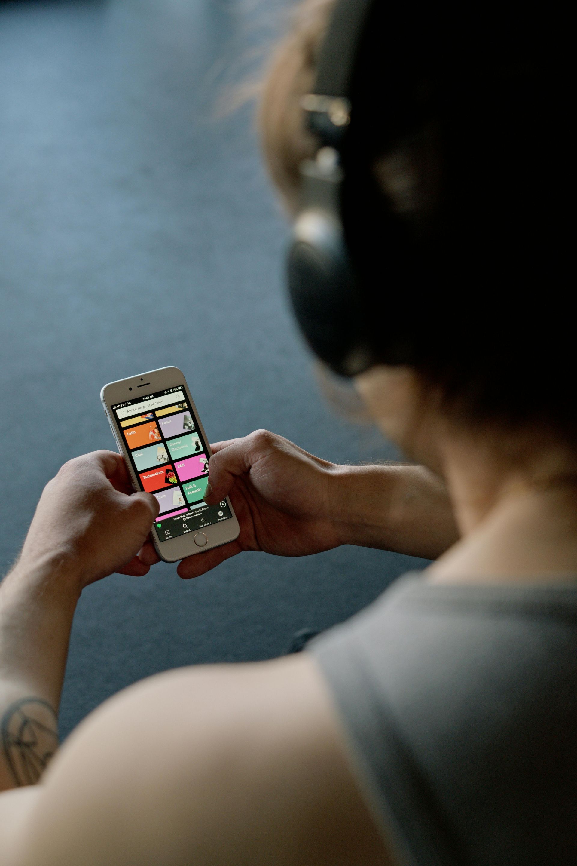 A person wearing headphones is holding a cell phone in their hands.