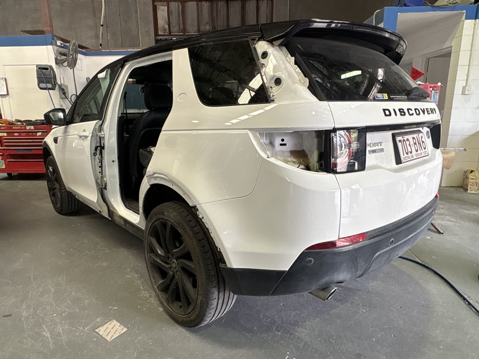 White Land Rover Discovery SUV in a repair shop with damaged door.— Airlie Beach Smash Repairs in Cannonvale, QLD