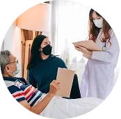 Doctor speaking with a masked patient and a visitor beside a hospital bed