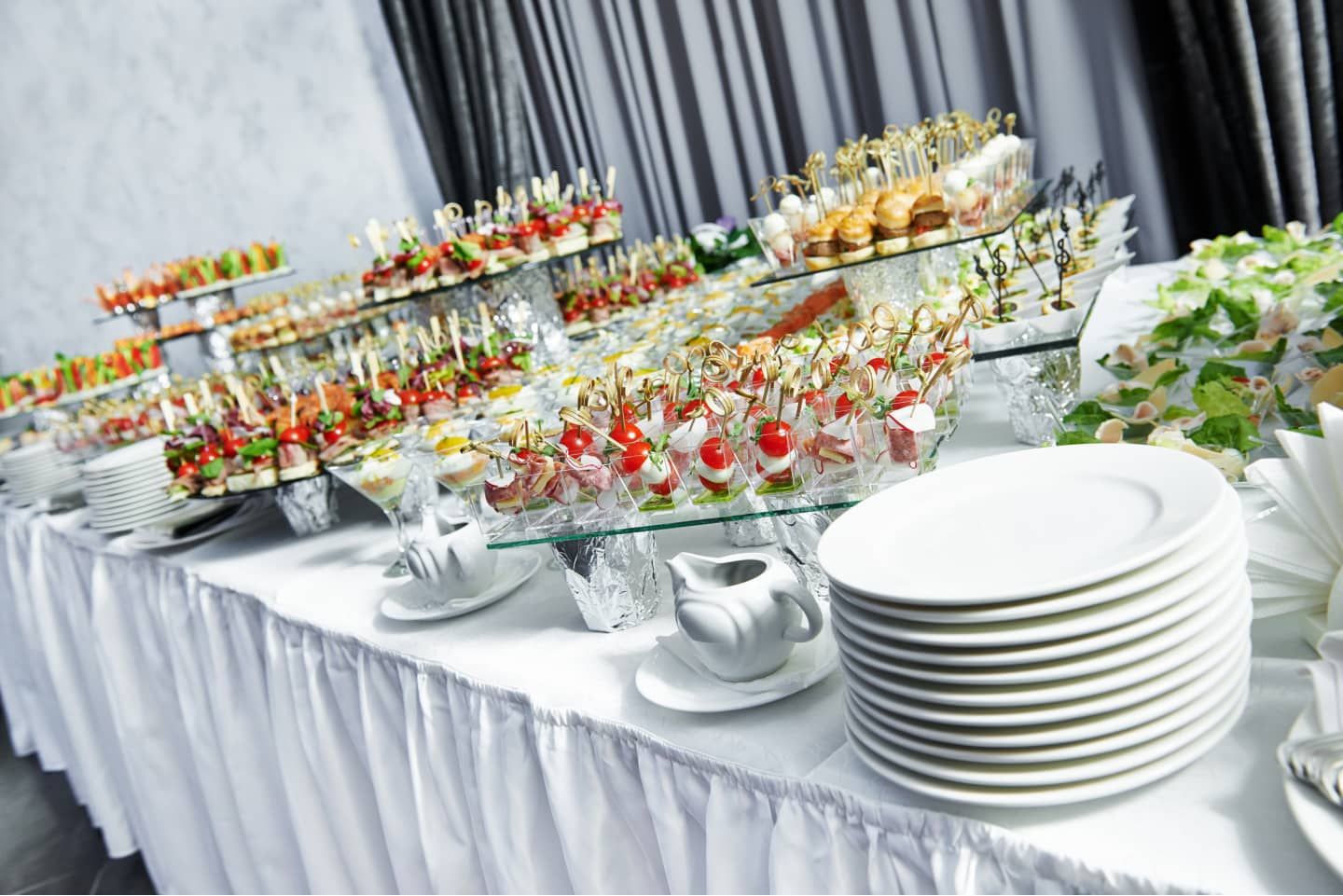 Buffet avec assiettes empilées, verres et desserts assortis lors d'un événement traiteur