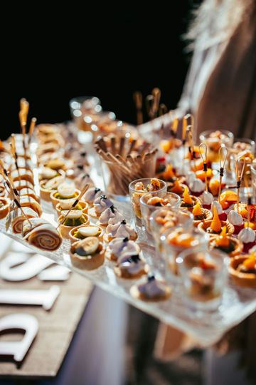 Assortiment de bouchées apéritives sur plateaux transparents, garnies d'agrumes et d'oranges, sur une table de traiteur.