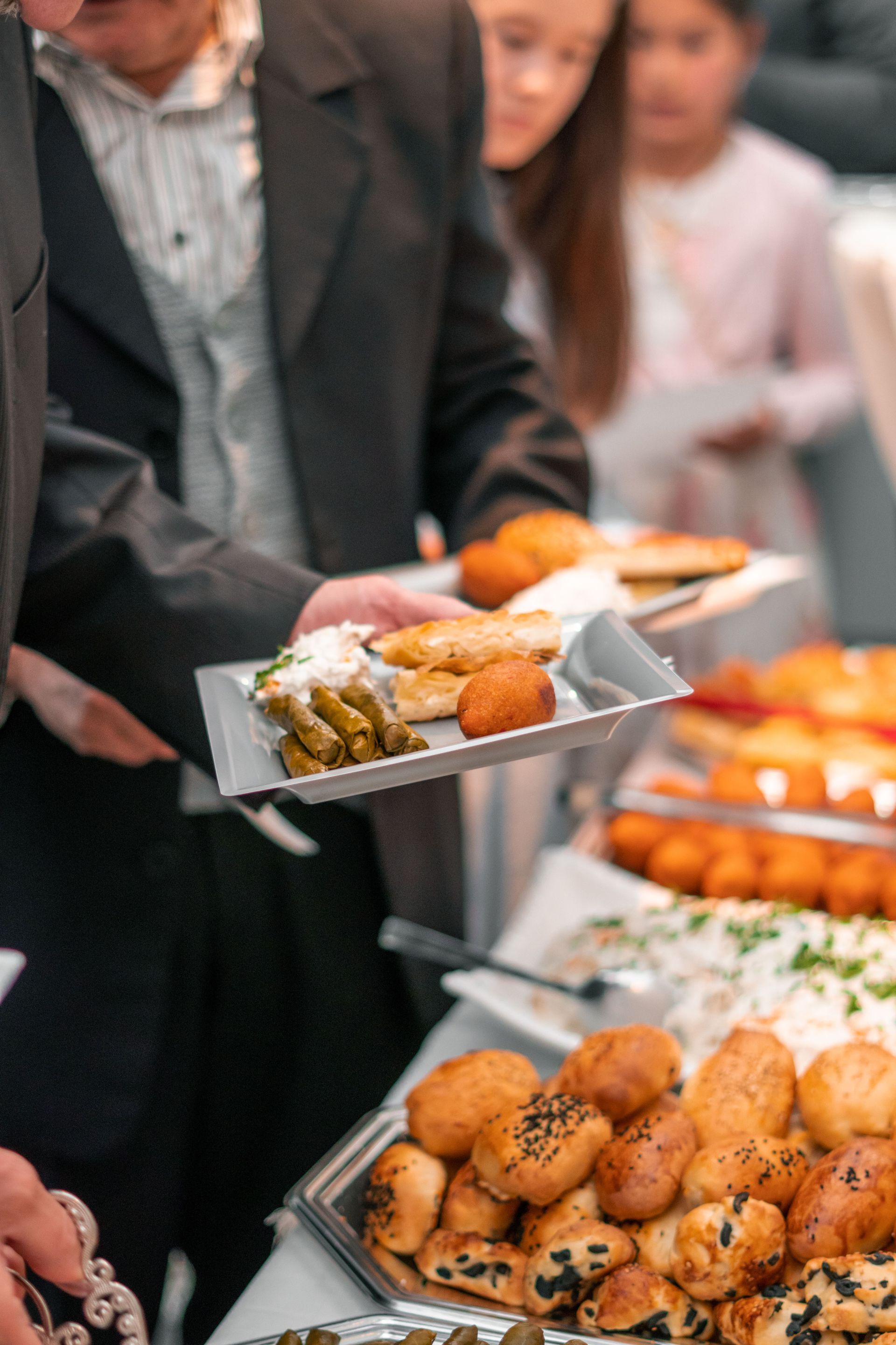 Une personne sert des amuse-gueules sur des plateaux à un buffet, avec des canapés assortis au premier plan.
