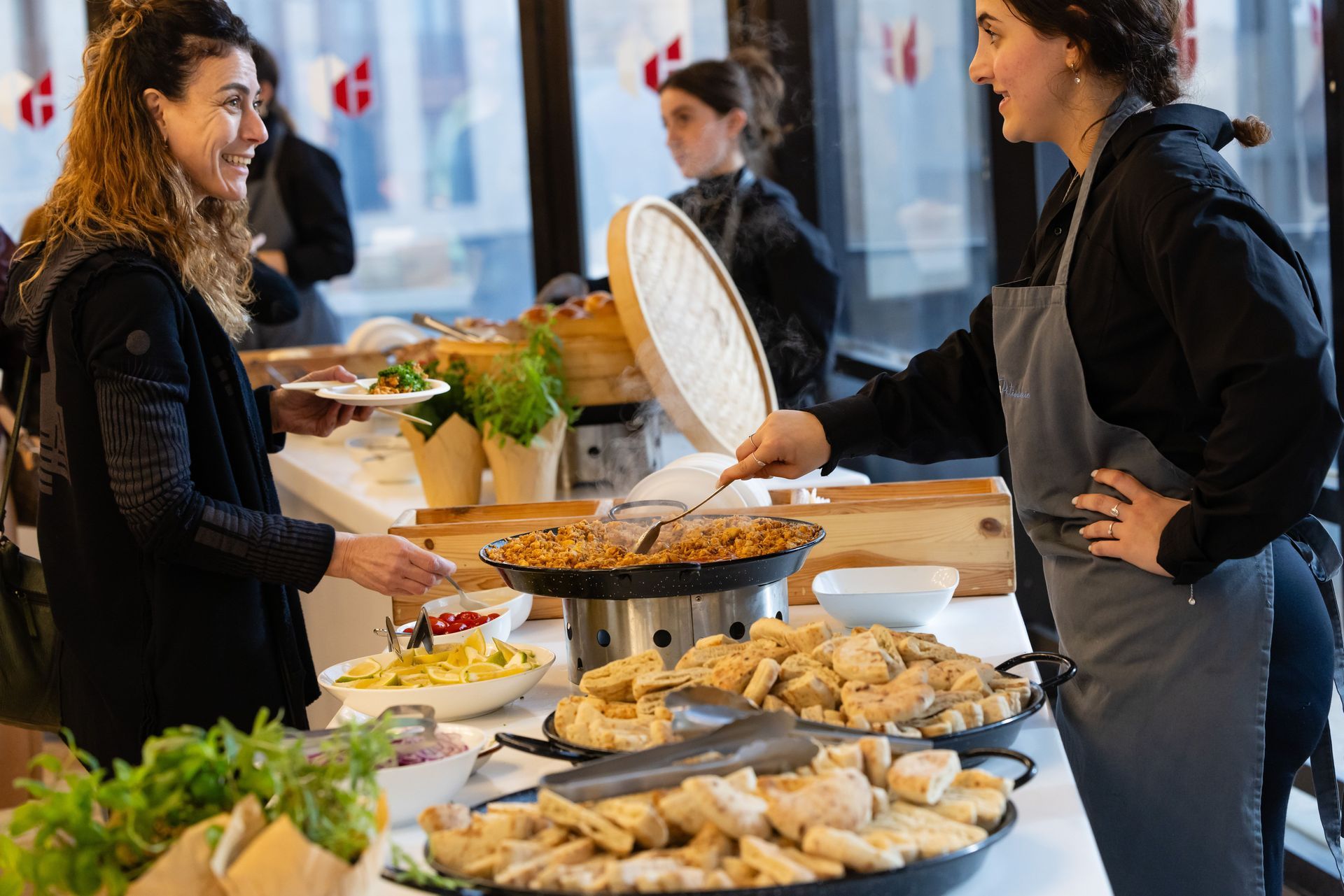 Des personnes se servent et choisissent des aliments à un buffet dans un cadre intérieur lumineux