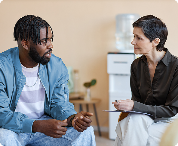 A man talking to a person holding a clipboard in an office setting.