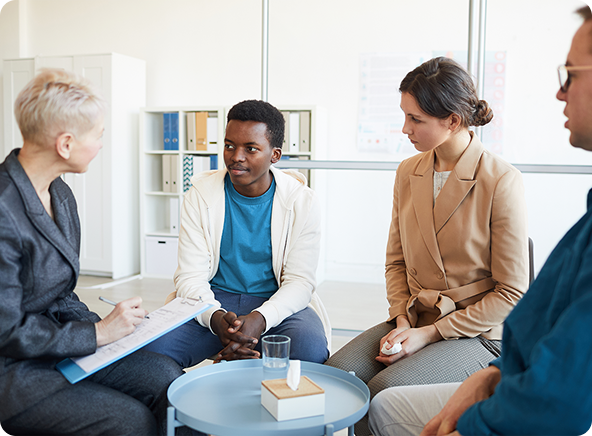 Group therapy session: People seated in a circle, one person speaking, the others listening attentively.