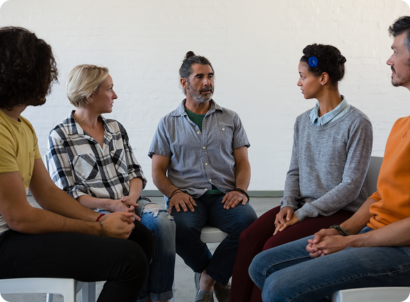 Group therapy session: five people seated in a circle, engaged in conversation.