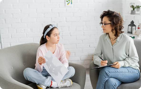 Girl in a consultation with a person taking notes. Both sit in armchairs.