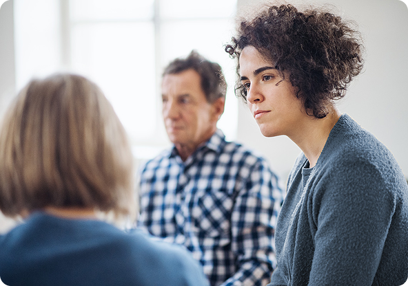 Group therapy session: woman listening intently, two others in background.