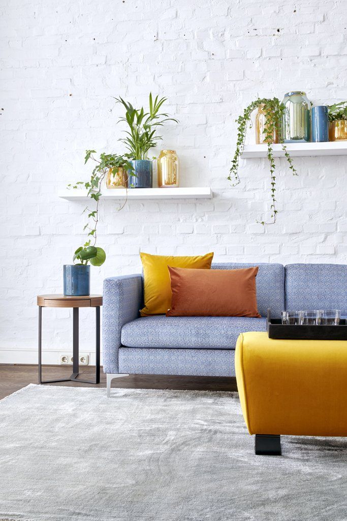 Ein Wohnzimmer mit einer blauen Couch und einem gelben Ottomanen.