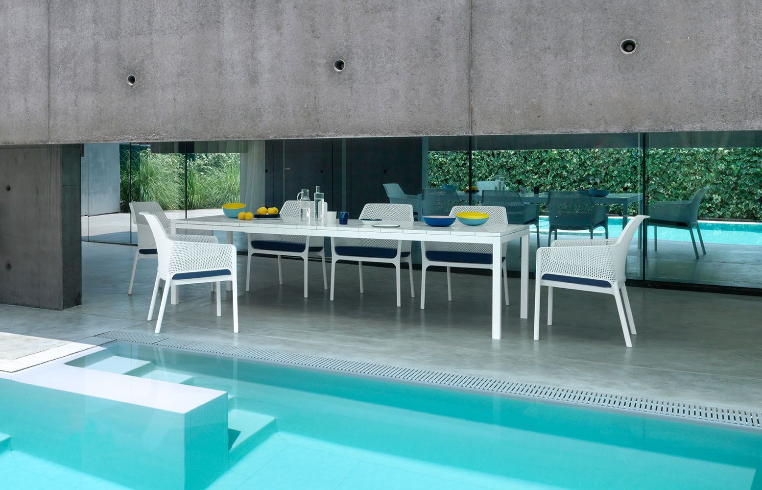 Ein Tisch und Stühle stehen neben einem Swimmingpool.