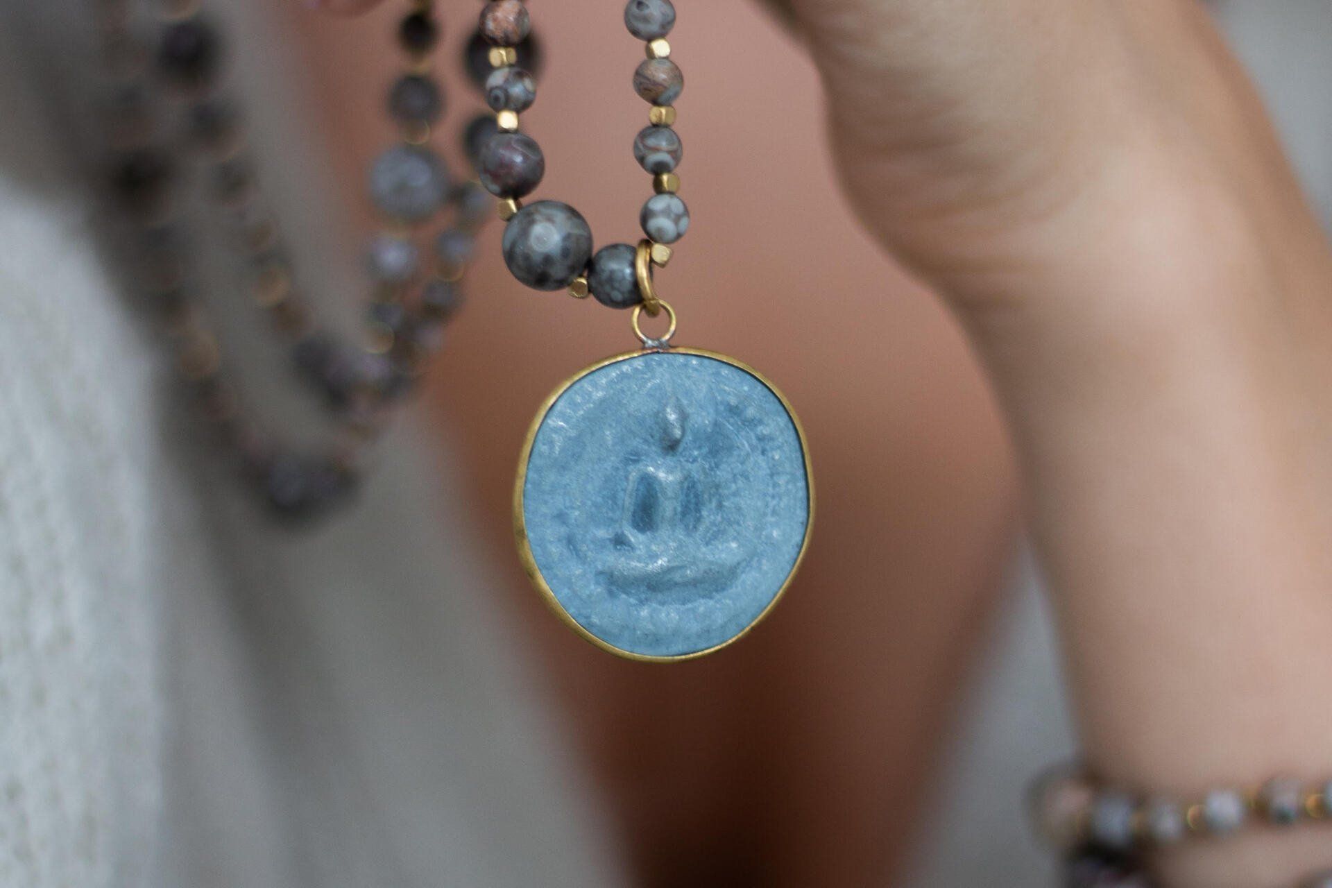 Eine Frau hält eine Halskette mit einem blauen Anhänger.
