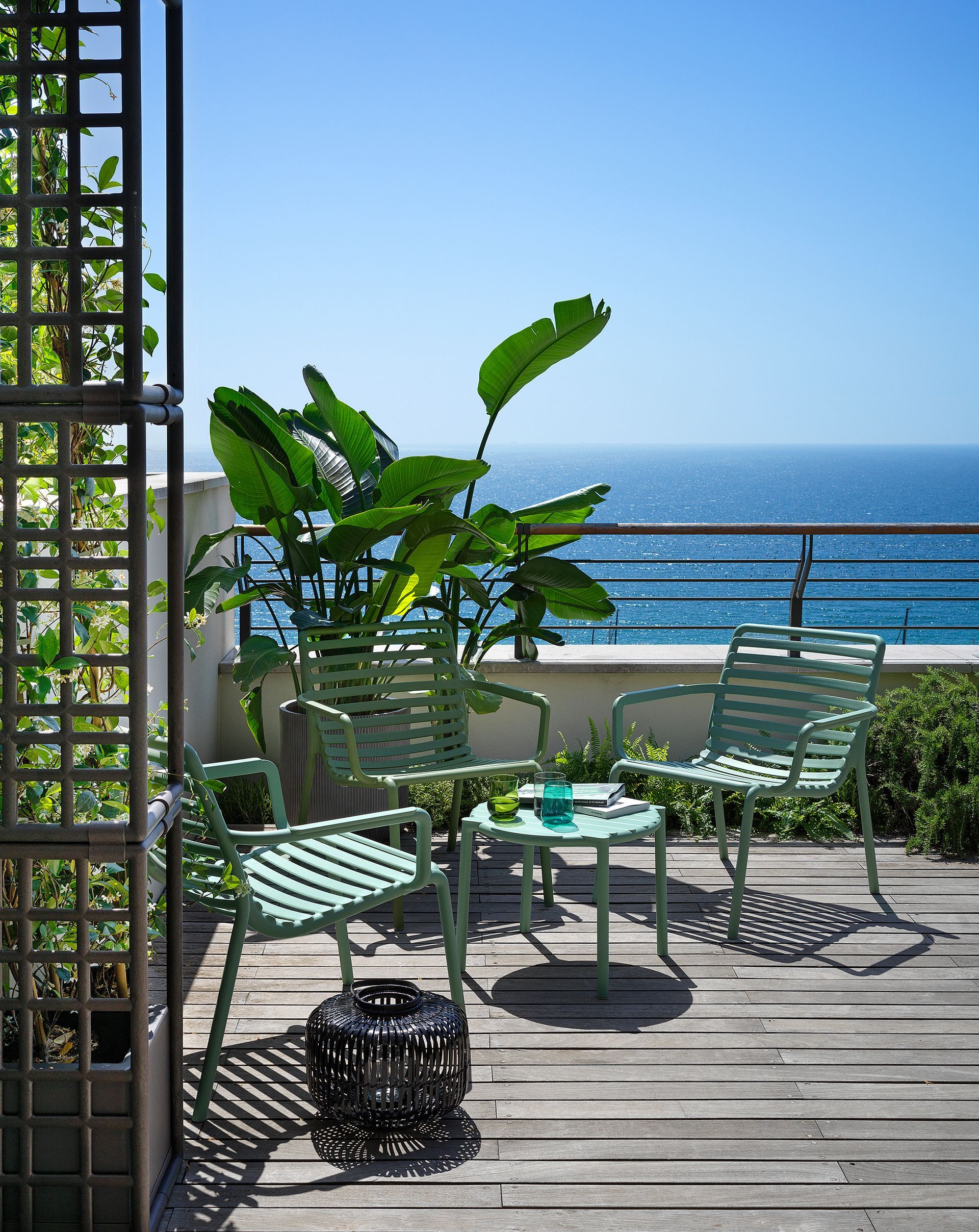 Ein Balkon mit Tisch und Stühlen mit Blick auf das Meer.