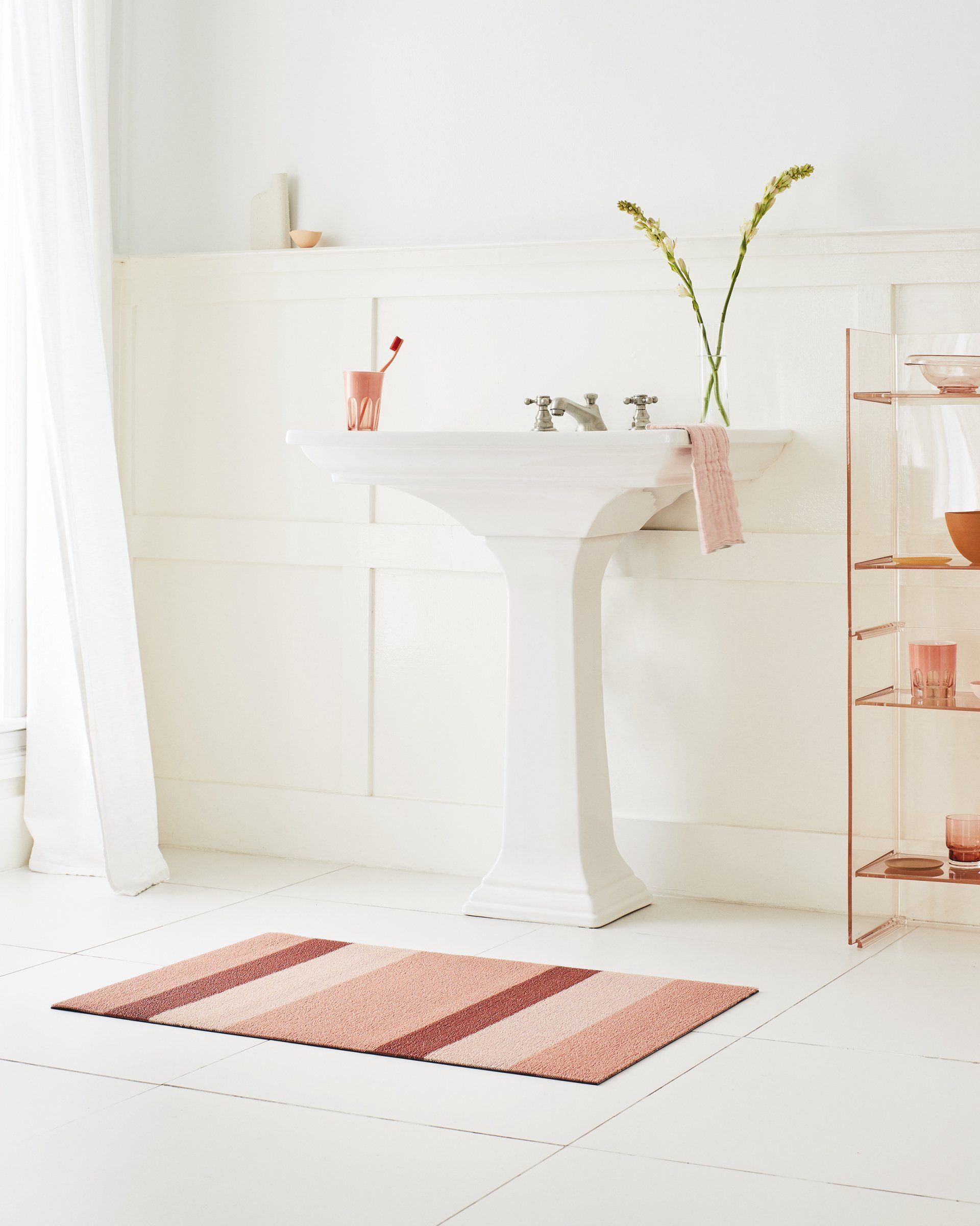 Ein Badezimmer mit Waschbecken und einem Teppich auf dem Boden