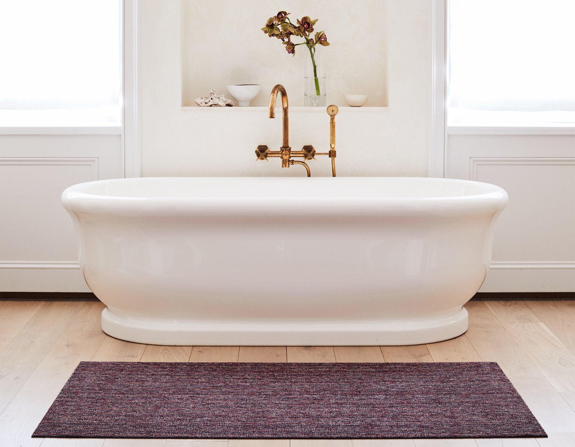 Im Badezimmer gibt es eine Badewanne und auf dem Boden liegt ein lila Teppich.