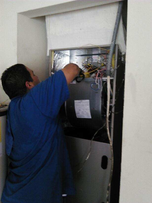 a man in a blue shirt working on an HVAC unit