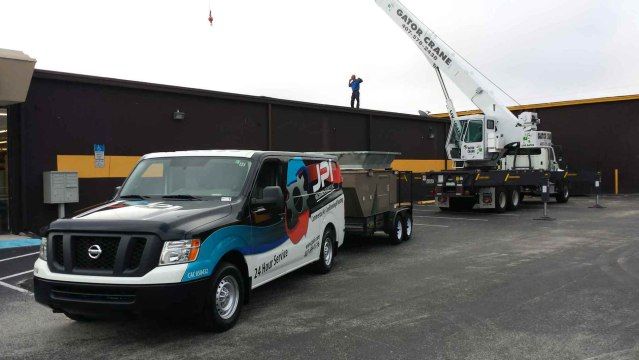 a van with a crane attached to it is parked in front of a building .