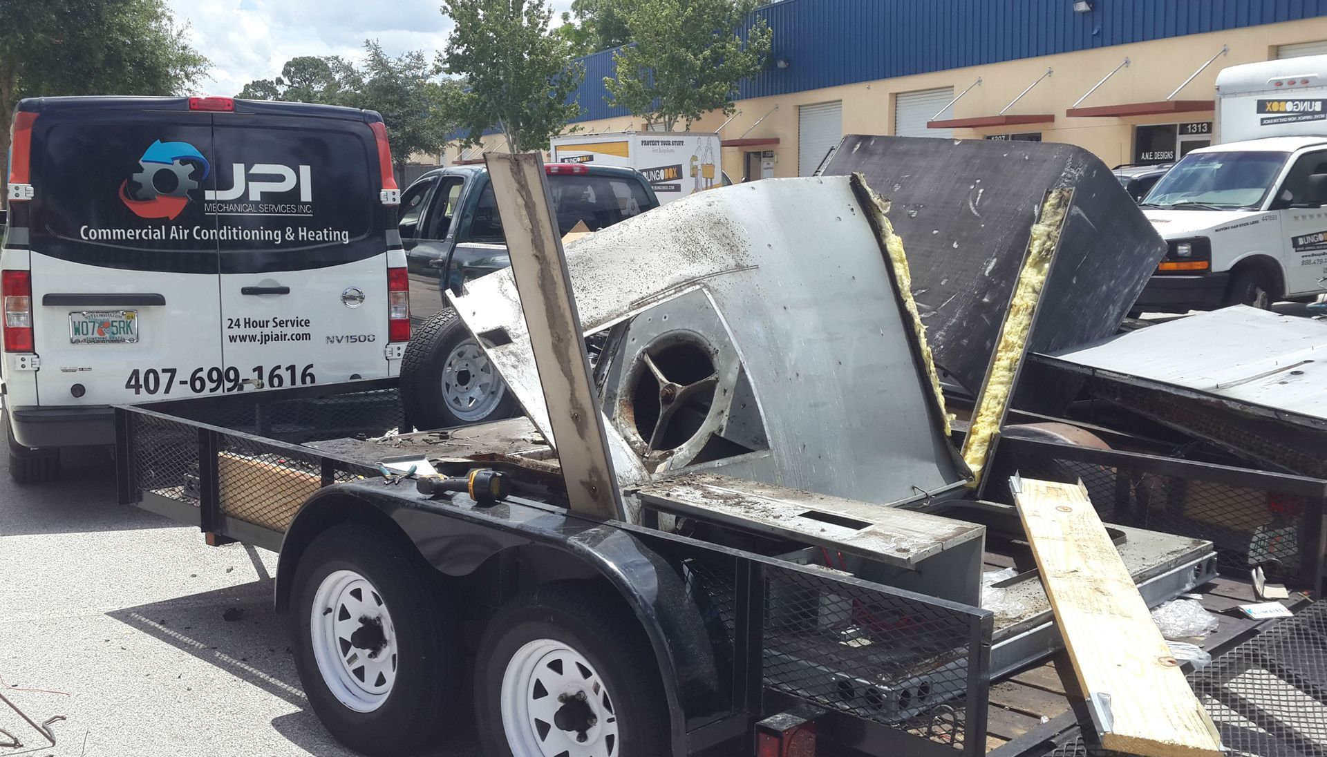 a jpi van is parked next to a trailer with a machine on it .