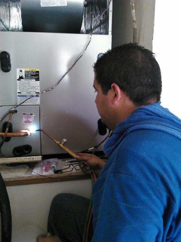 a man in a blue shirt is working on an air conditioner