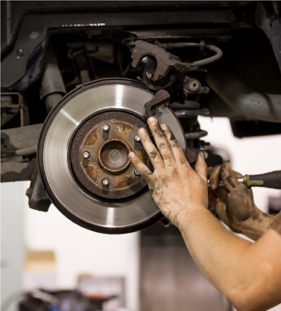 Mechanic working on a car brake rotor and wheel assembly with hands covered in grease