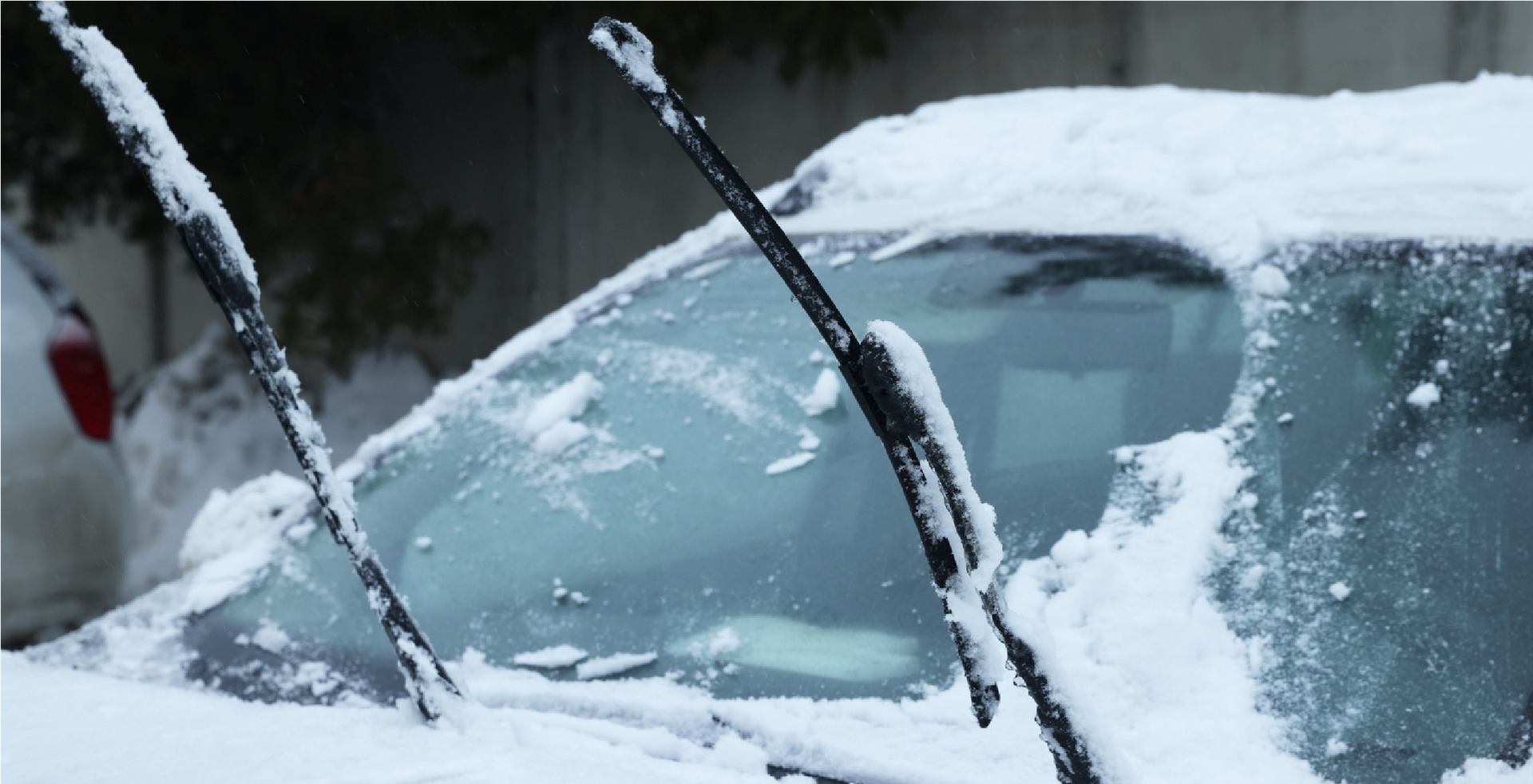 Snow-covered car windshield with wipers raised in winter weather