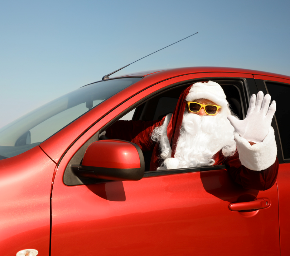 Santa waving from a red car with the window down, wearing sunglasses and a white beard
