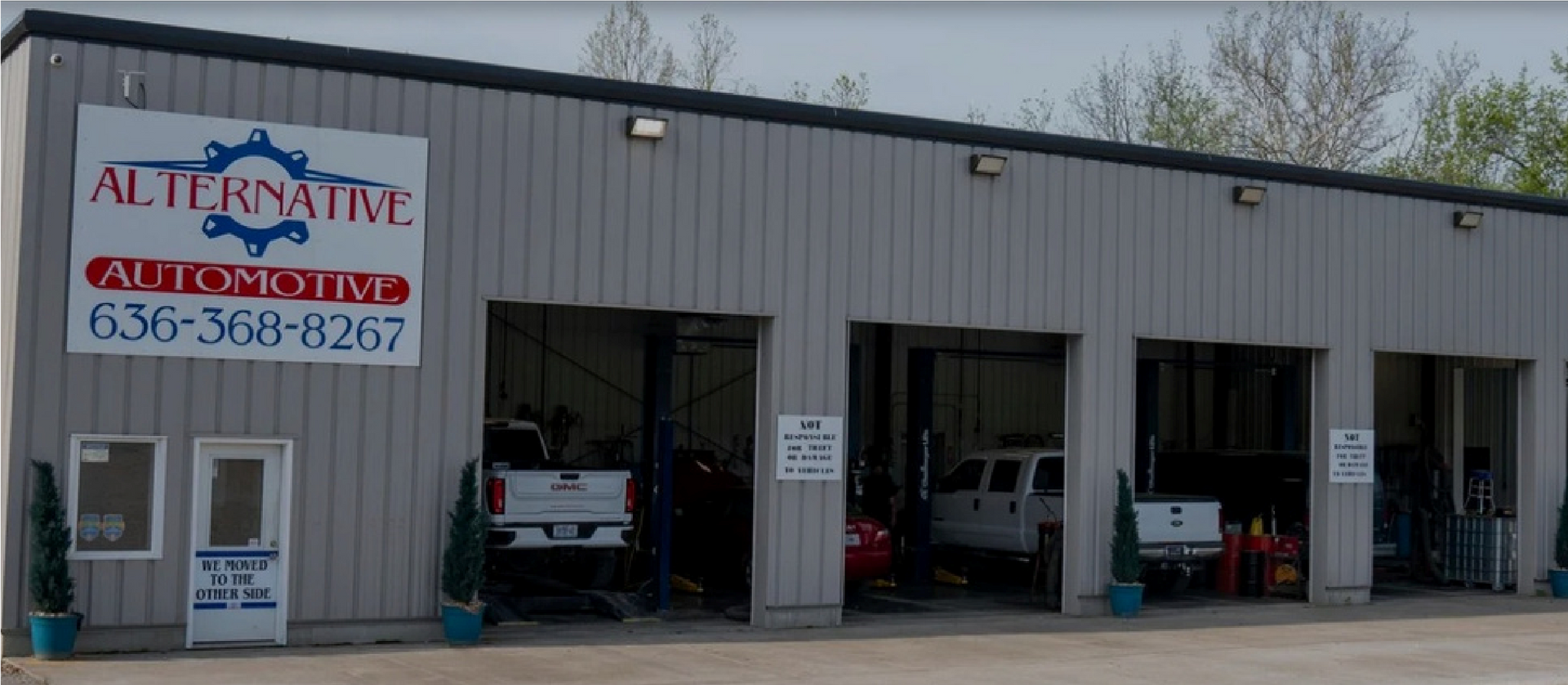 Auto repair shop exterior with open service bays and parked vehicles