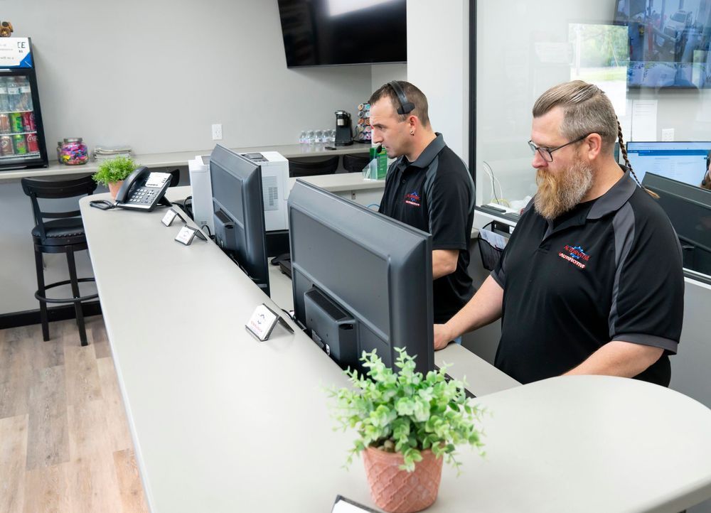Two people working at computers in a modern office reception area