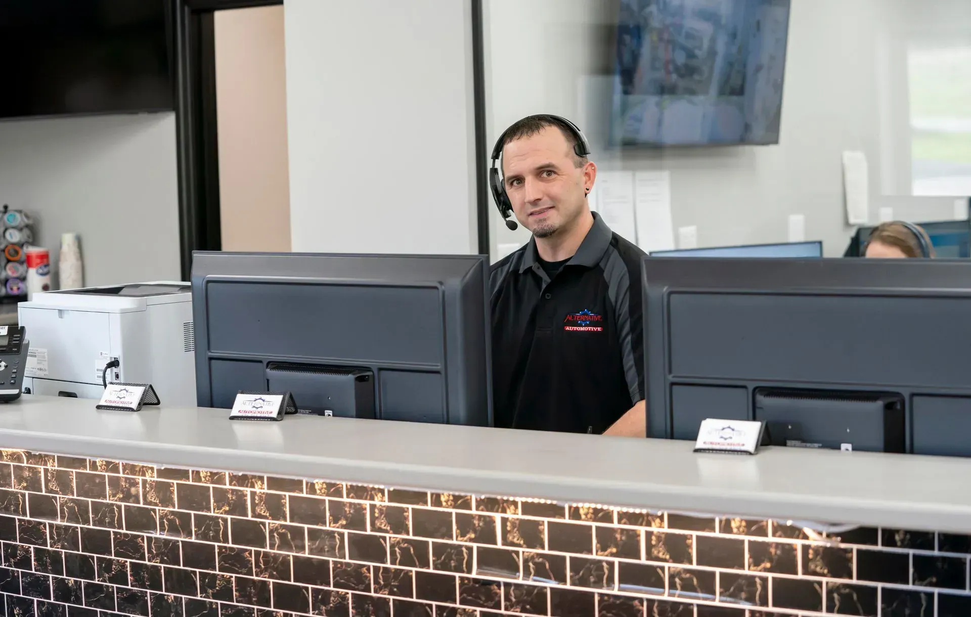 Man standing behind a front desk with computer monitors in a modern lobby