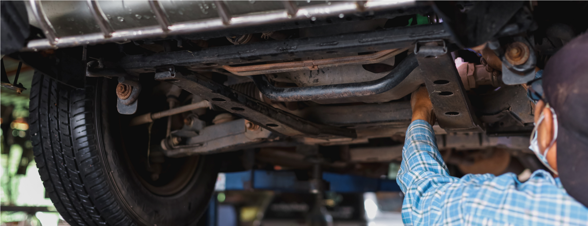 Mechanic inspecting the underside of a vehicle on a lift in a garage