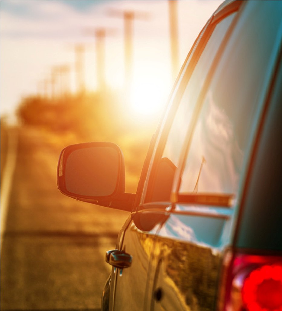Car side mirror and door reflecting a sunset over a road with blurred power lines in the distance