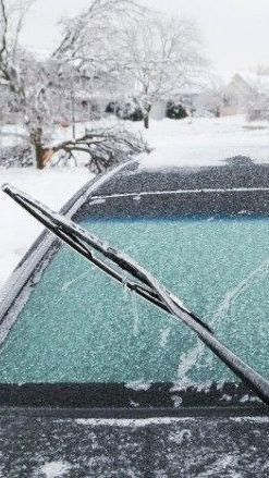 Windshield wipers on a car covered in snow during a snowy winter scene