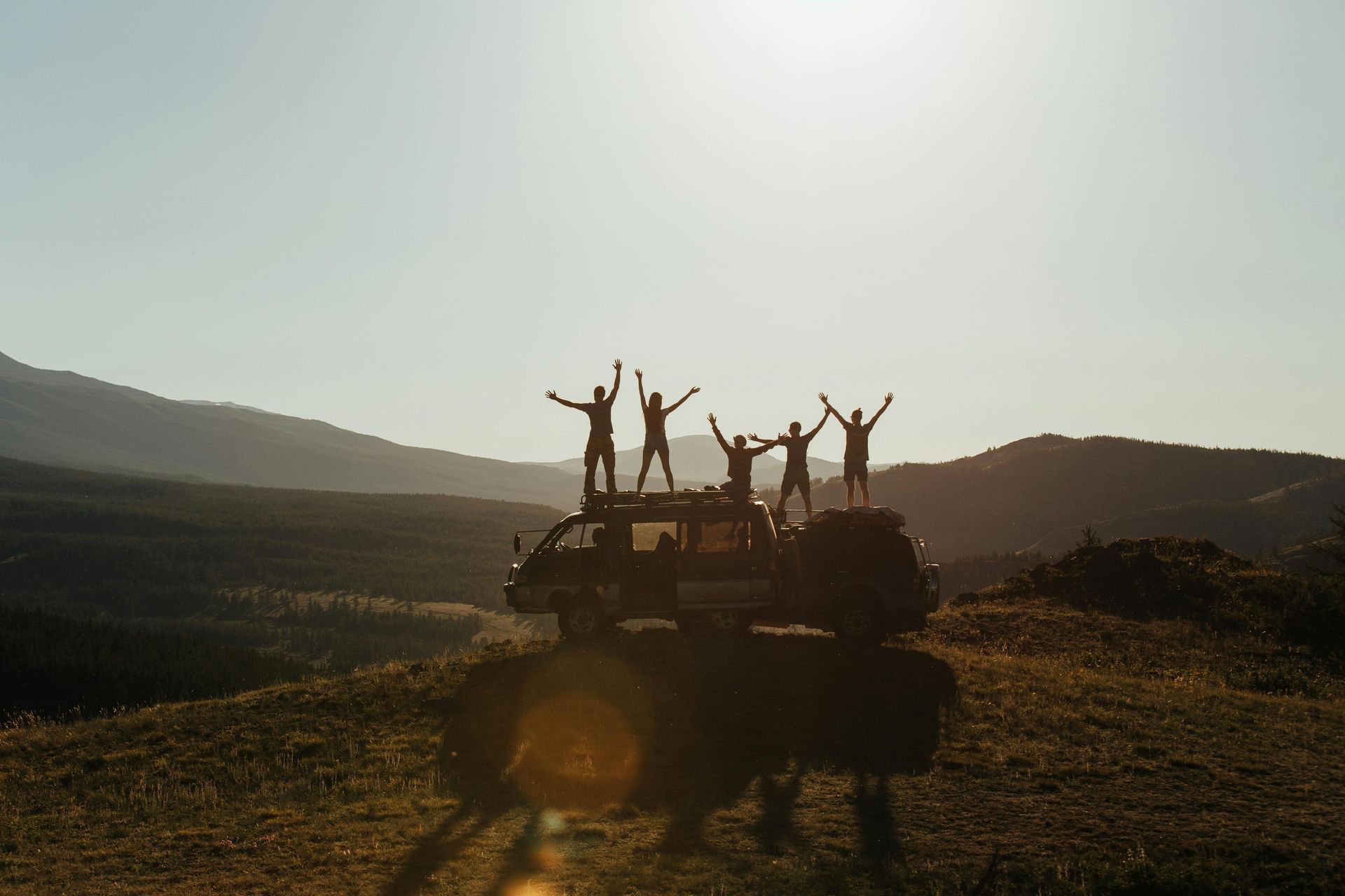 A group of people are standing on top of a truck with their arms in the air.