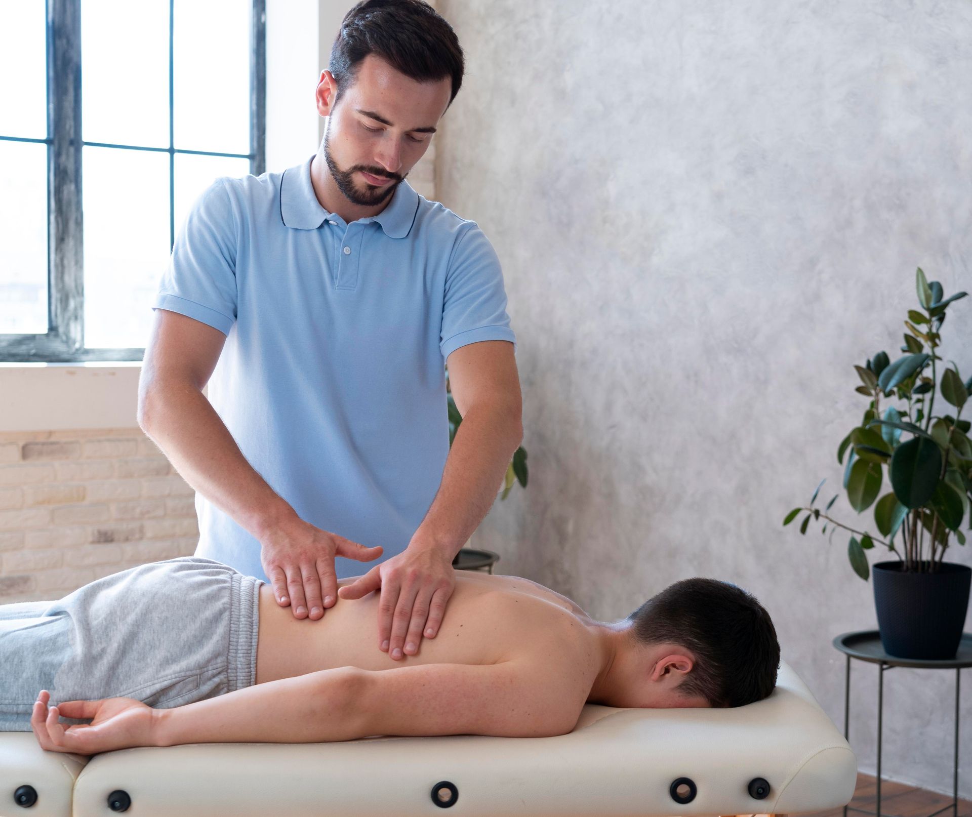 Therapist giving a back massage on a treatment table in a bright room