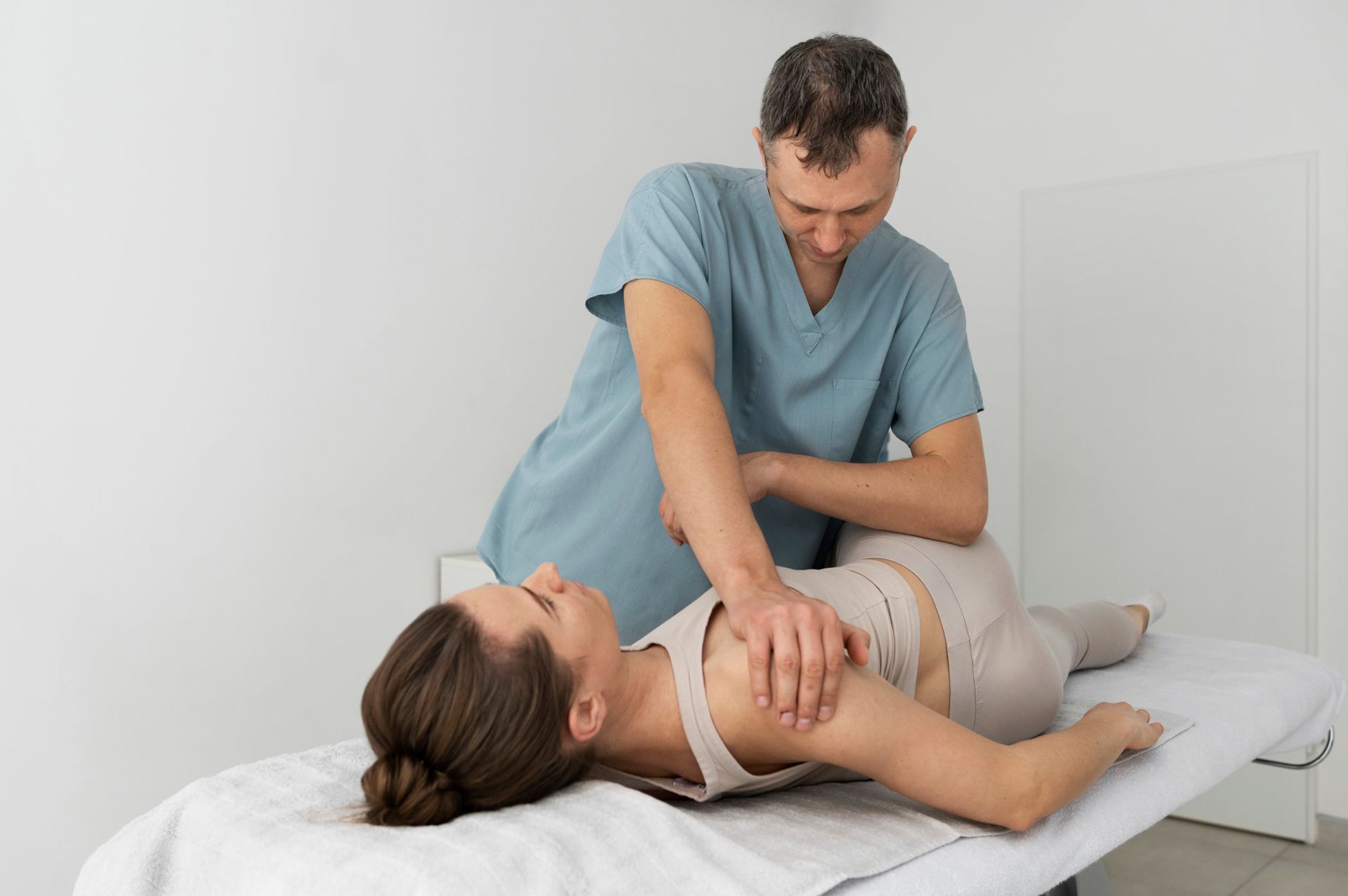 Therapist treating a patient on a massage table in a bright clinic room