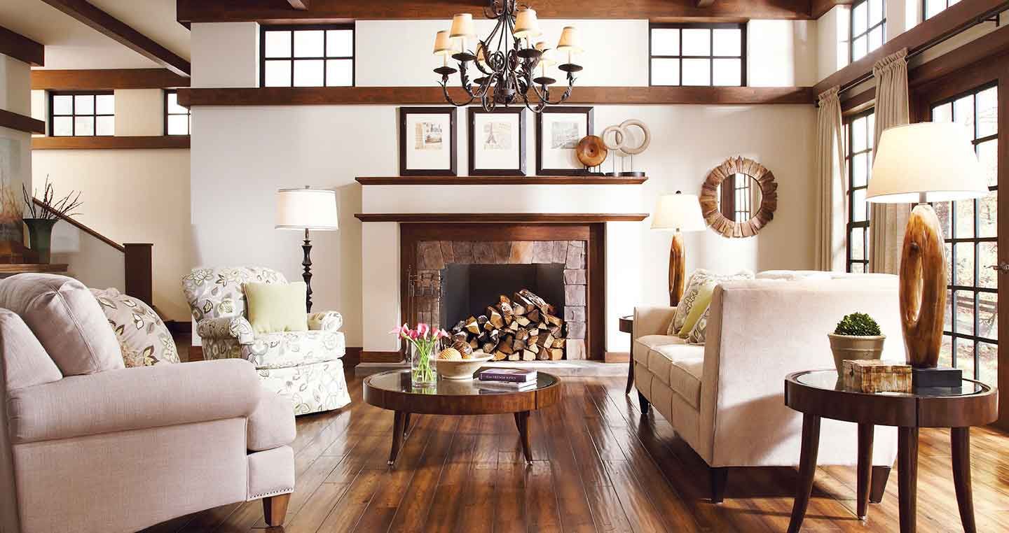 Cozy living room with fireplace, white walls, and wooden accents, furnished with sofas, chairs, and a round coffee table.