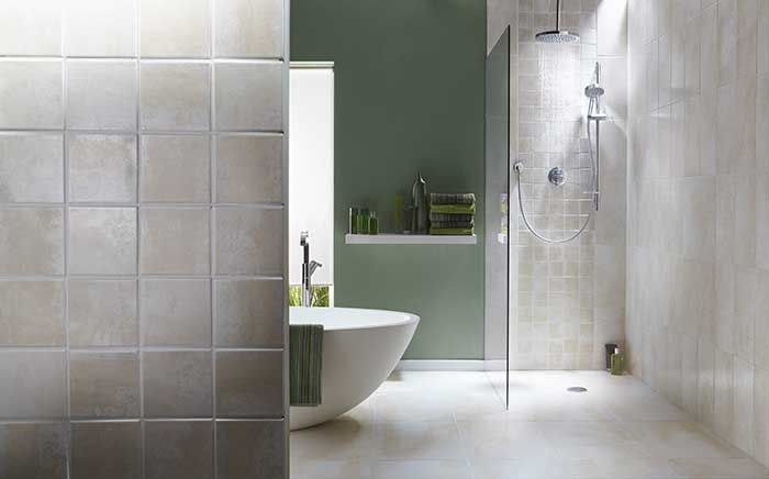 Modern bathroom with beige tile, walk-in shower, and a freestanding tub against a green wall.