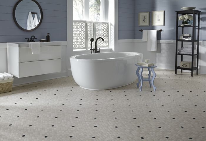 Bathroom with white tub, blue walls, patterned floor, and a pedestal sink.