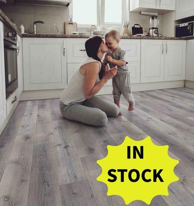 Woman kissing a child in a kitchen with gray flooring; a yellow