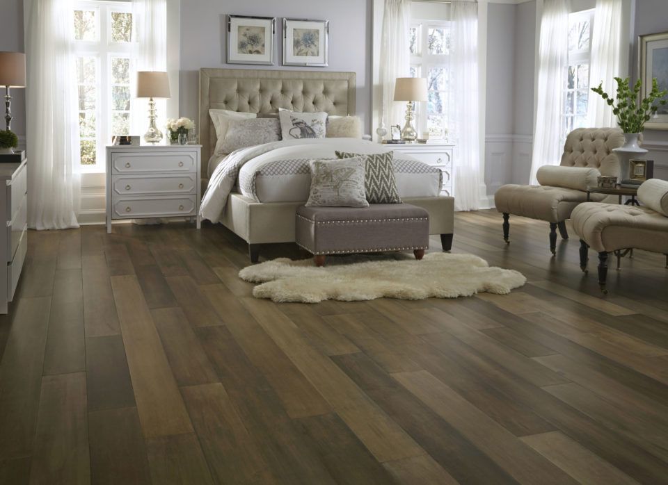 Bedroom with hardwood floor, tufted headboard bed, two bedside tables, and sitting area.