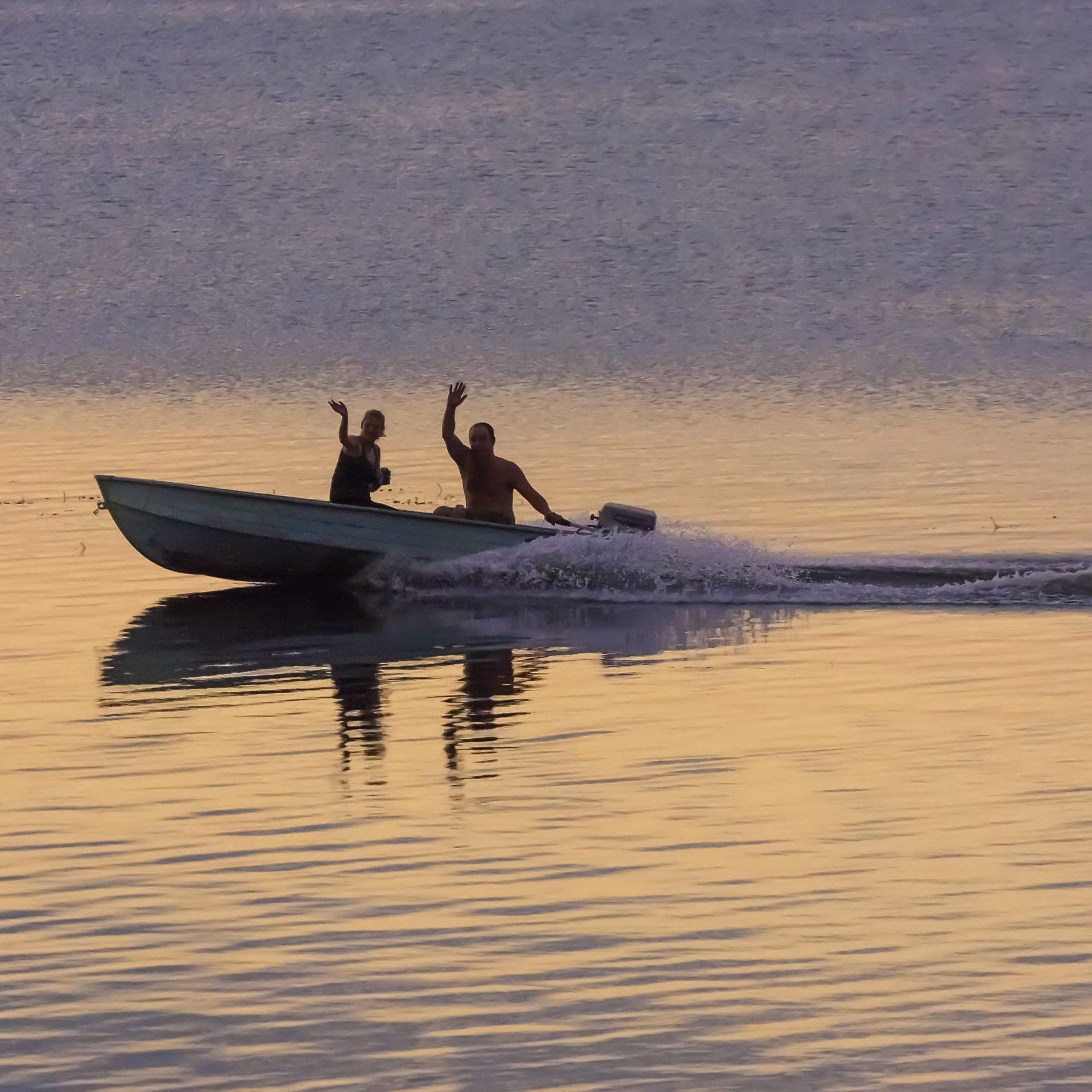 Two people wave from boat Two people wave from boat