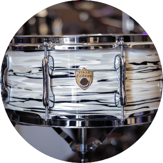 White and black swirled snare drum with chrome hardware, a gold badge, and a stand.
