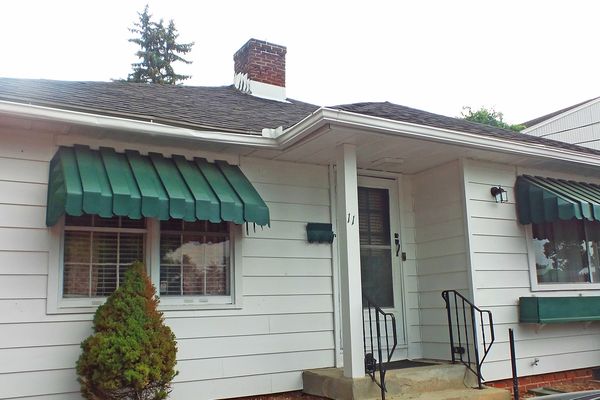 A white house with green awnings on the windows
