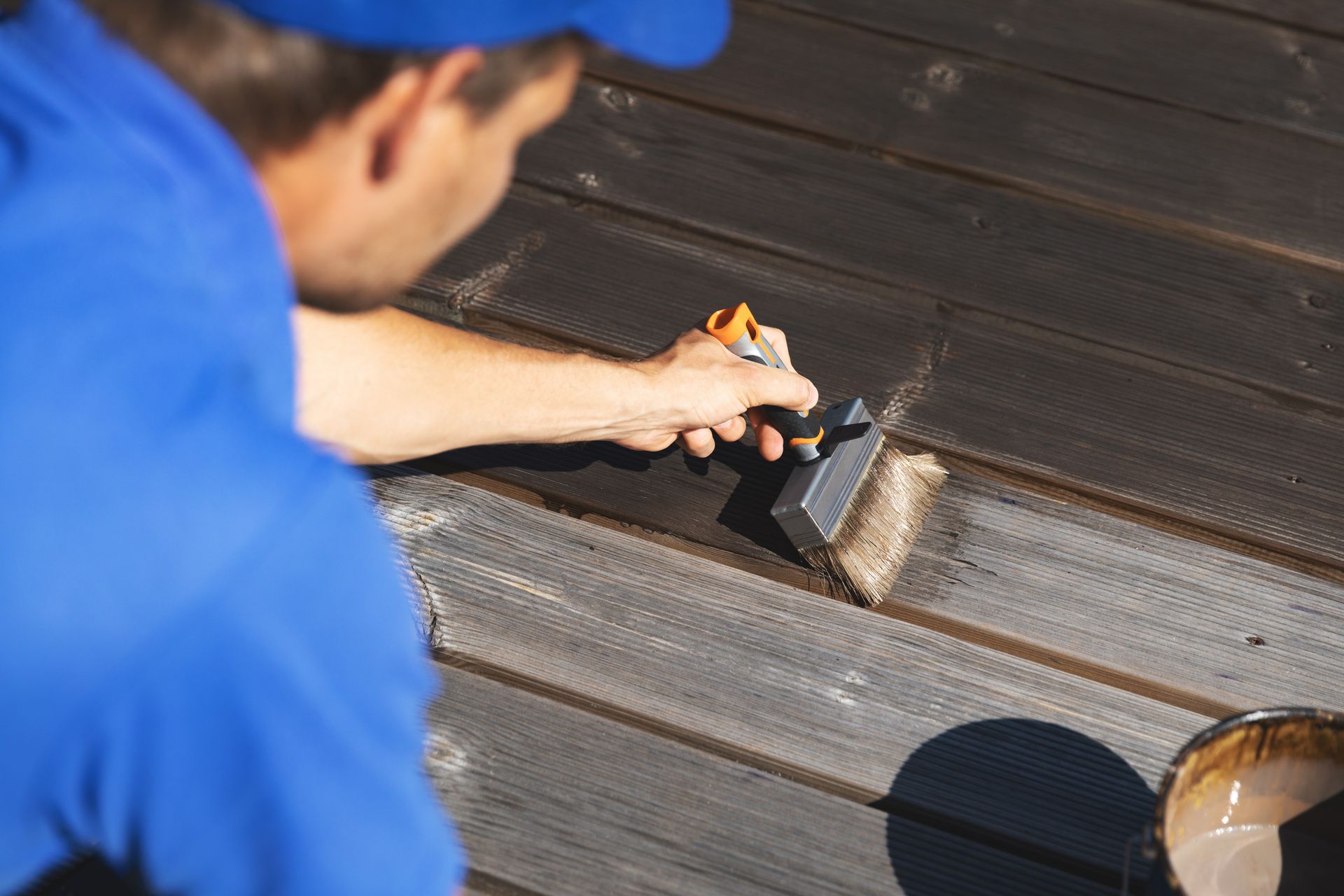 Worker using a brush to apply coating on a dark roof surface
