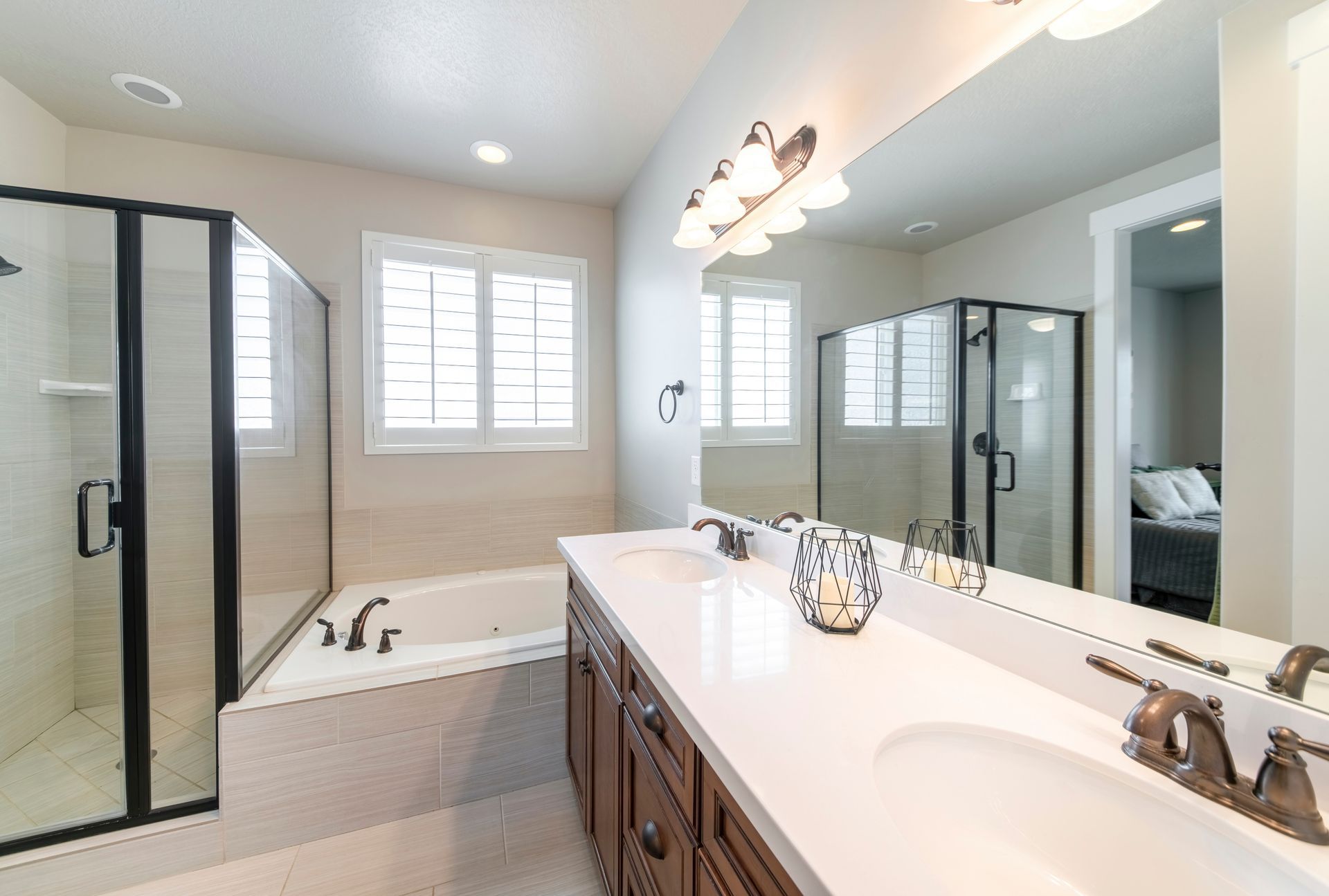 Bright bathroom with glass shower, soaking tub, double vanity, and large mirror￼