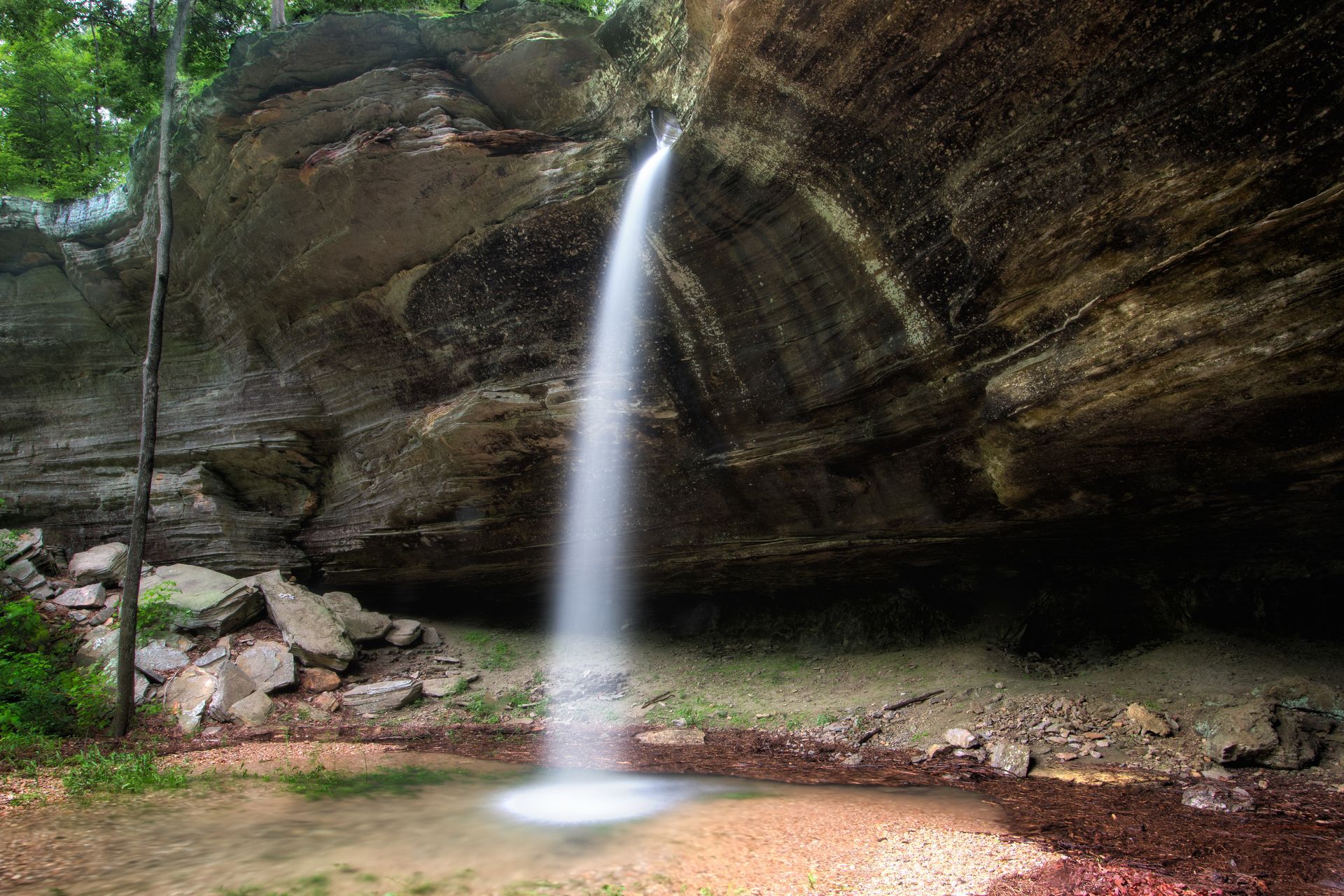 a waterfall is coming down a rocky cliff in the woods .