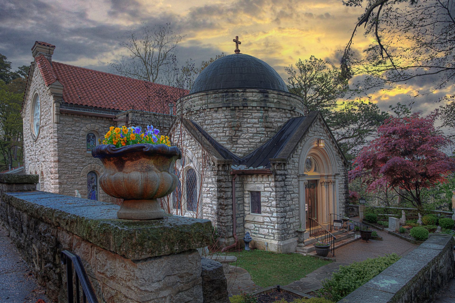 a church with a dome on top of it and a vase of flowers in front of it .