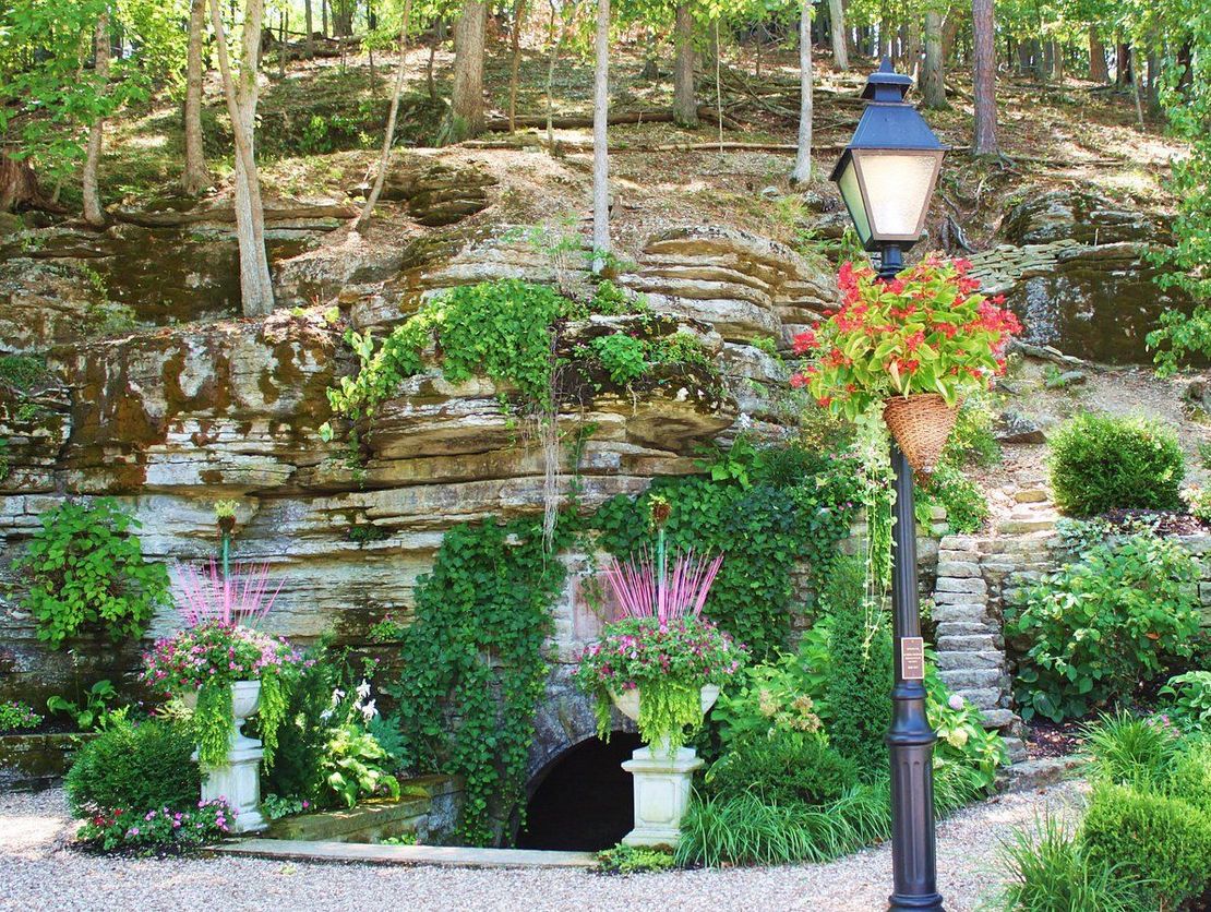 a cave filled with flowers and plants in a garden .