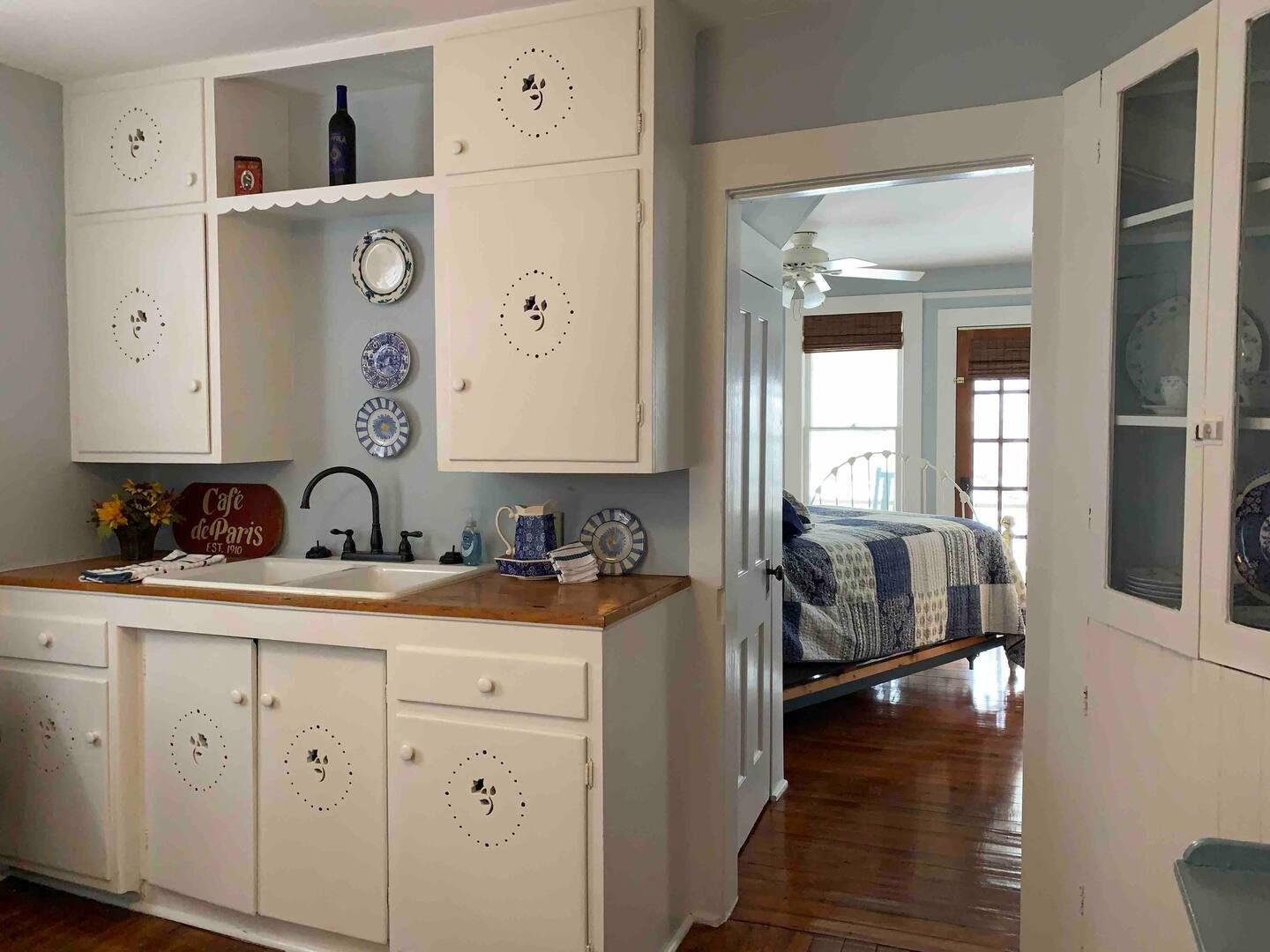 a kitchen with white cabinets , a sink , and a glass cabinet .