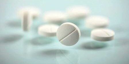 A group of white pills on a blue surface.